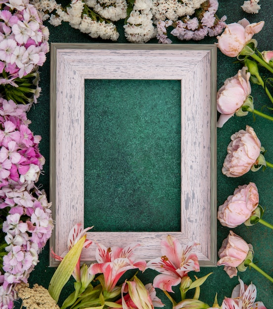 Top view of gray frame with light pink flowers on a green surface