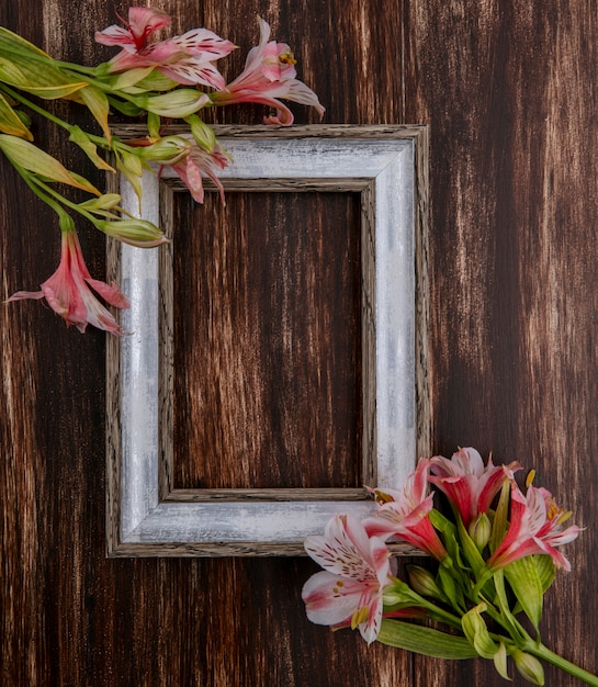 Top view of gray frame with pink lilies on a wooden surface