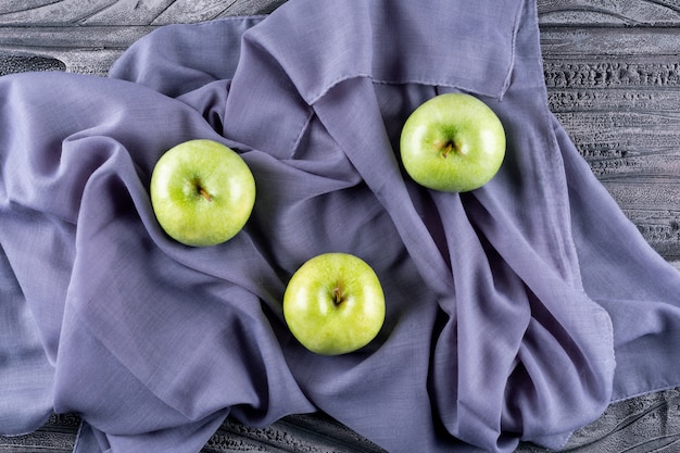 Free photo top view green apples on gray cloth on gray wooden  horizontal