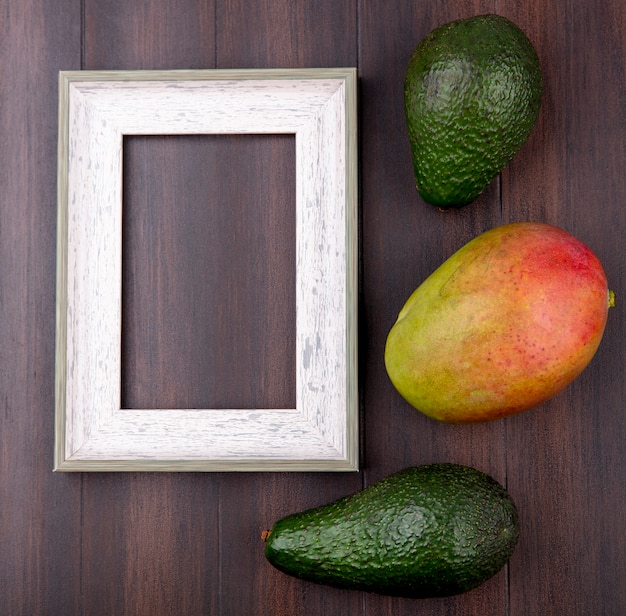 Top view of green avocado with mango on a wooden surface