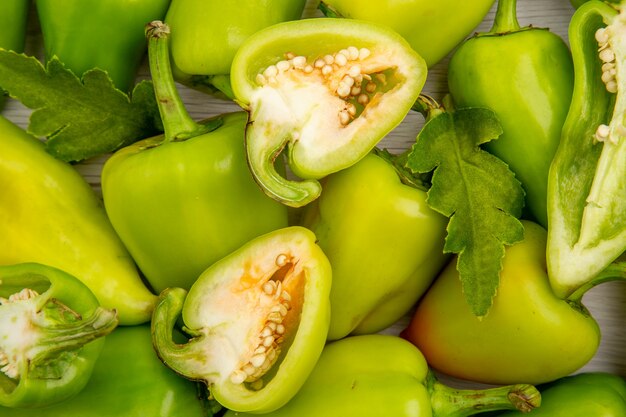 Free photo top view green bell-peppers inside frame on the white desk