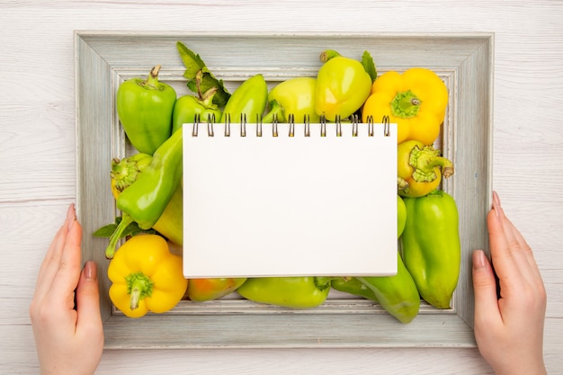 Free Photo top view green bell-peppers inside frame on the white table