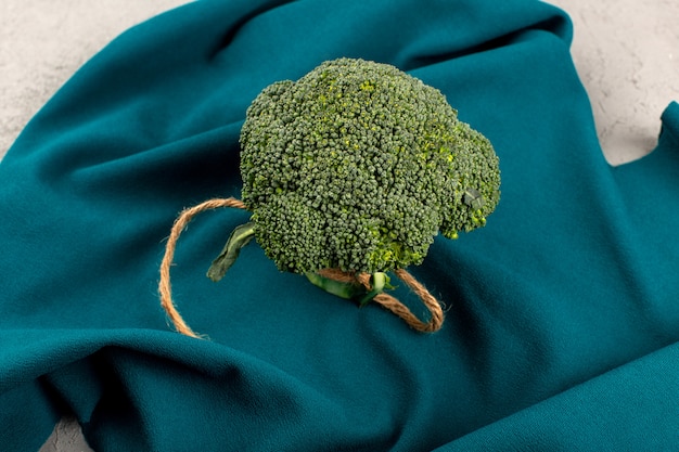 Free photo top view green broccoli ripe fresh on the blue tissue and grey floor