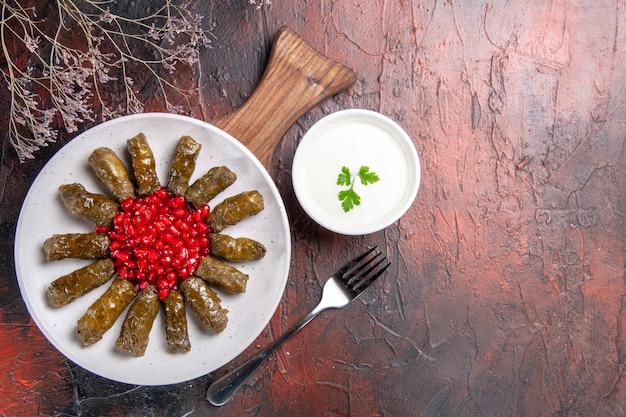 Top view of green leaf dolma with yogurt on dark surface