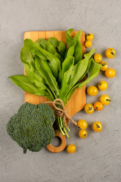 top view green leafs broccoli along with yellow tomatoes on the grey background