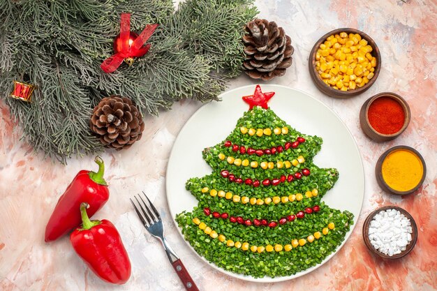 Top view green salad in new year tree shape with seasonings on the light background