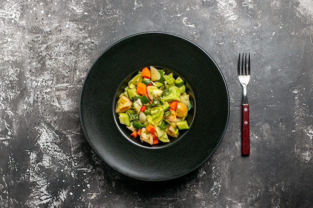 Free photo top view green tomato salad on oval plate a fork on dark background