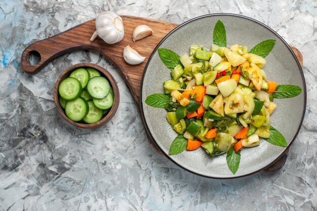 Top view green tomato salad on oval plate garlic on cutting board on dark background