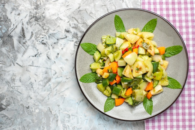 Top view green tomato salad on oval plate pink tablecloth on dark background free space