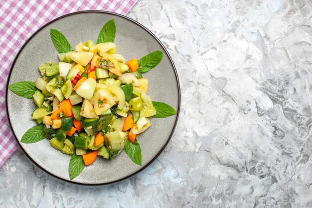 Top view green tomato salad on oval plate pink tablecloth on grey background with copy space