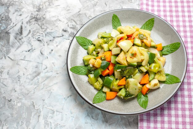 Top view green tomato salad on oval plate pink tablecloth on grey background