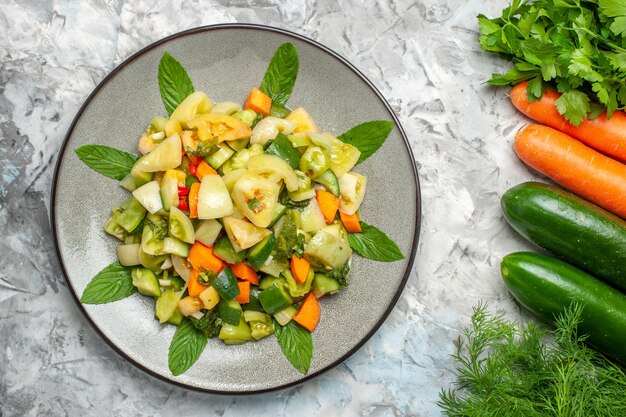 Top view green tomato salad on oval plate vegetables on dark background