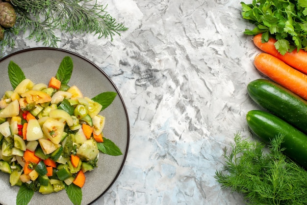 Top view green tomato salad on oval plate vegetables on dark surface