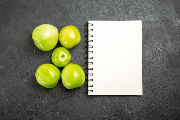 Top view green tomatoes a notebook on dark surface