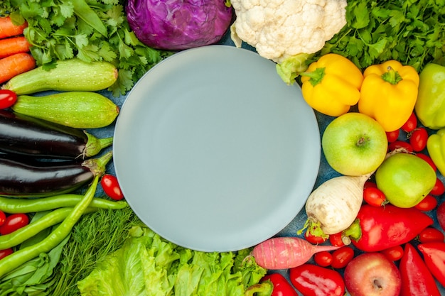 Top view grey round plate zucchini cherry tomato dill aubergine coriander parsley radish apples lettuce cauliflower bell peppers