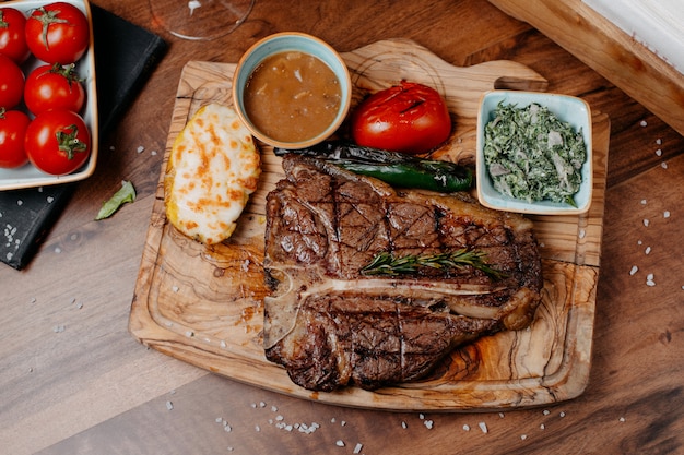 Free Photo top view of griled beef steak served with vegetables and sauce on a wooden board