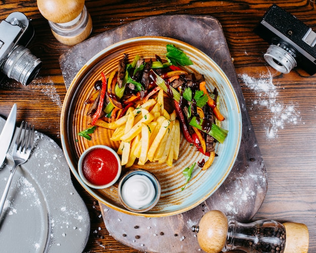 Free photo top view of grilled beef meat with vegetables served with french fries and sauces on a plate