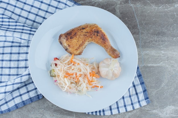 Top view of grilled chicken and sauerkraut on white plate. 