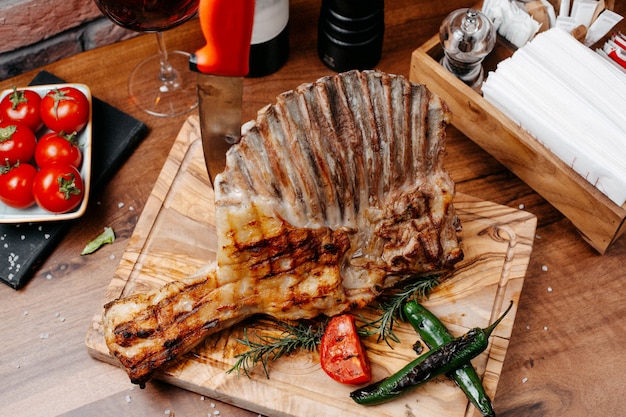 Free photo top view of grilled ribs served with vegetables on a wooden board