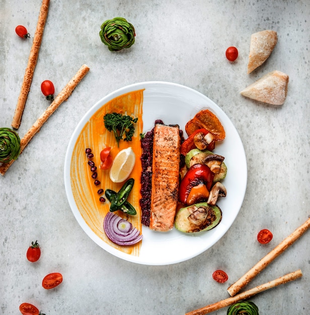 Free Photo top view of grilled salmon steak with vegetables lemon and spices on a white plate on white