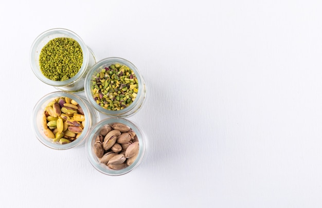 Free Photo top view ground, milled, crushed or granulated pistachios in glass jars on white 