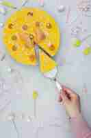 Free photo top view of hand cutting cake slice with birthday decorations