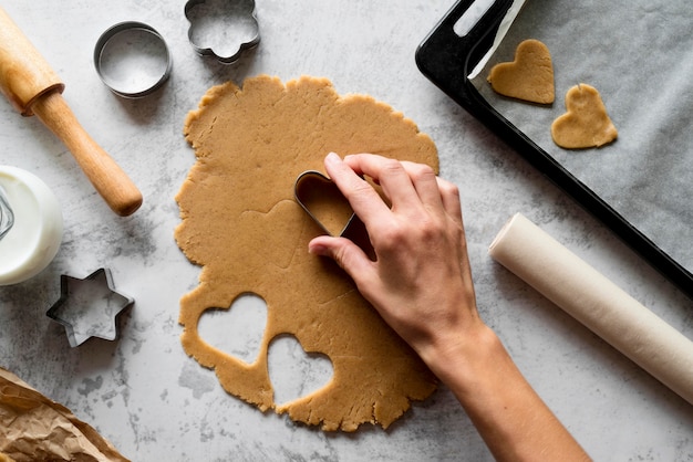 Free Photo top view hand cutting dough with shapes