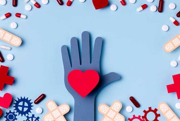 Free photo top view hand holding heart surrounded by pills