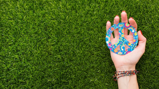 Top view of hand holding peace sign on grass with copy space