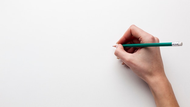 Top view of hand holding a pencil with copy space