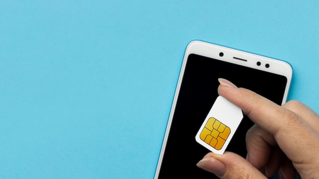 Top view of hand holding sim card with smartphone and copy space