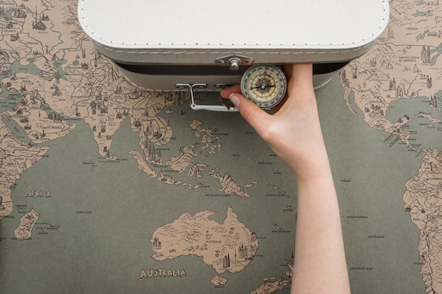 Top view of hand taking a compass from the suitcase