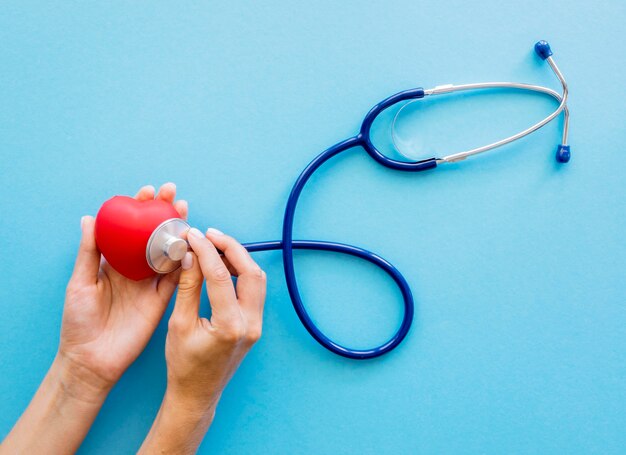 Top view of hands checking heart shape with stethoscope