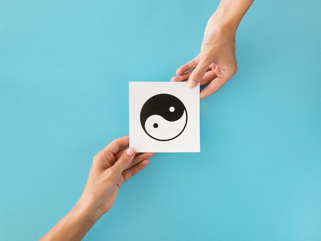 Free photo top view of hands exchanging ying and yang symbol