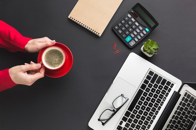 Top view of hands holding coffee cup on work desk