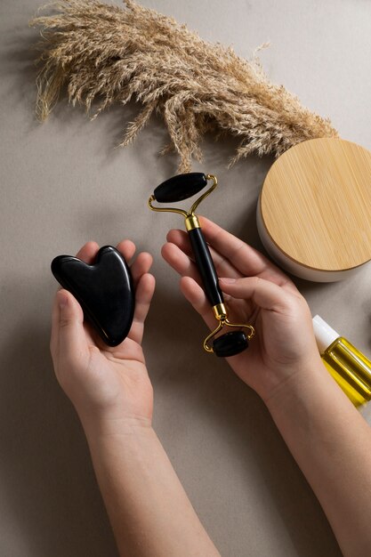 Top view hands holding face roller and gua sha