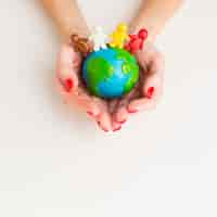 Free photo top view of hands holding globe with people figurines