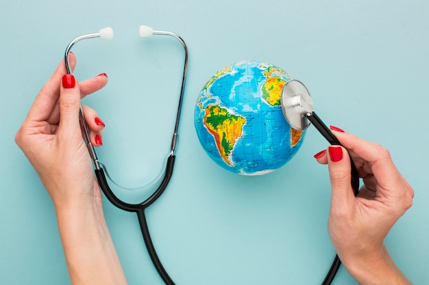 Free Photo top view of hands holding stethoscope with globe