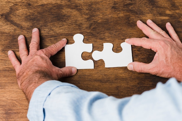 Free photo top view hands making puzzle on wooden table