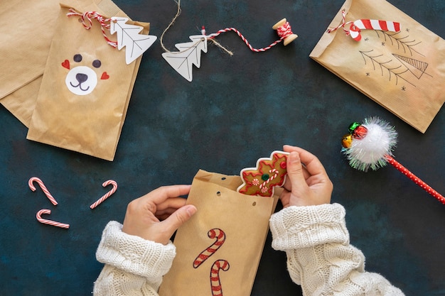 Free Photo top view of hands putting treats inside christmas gift bags