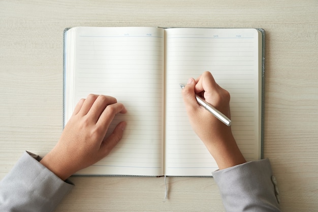 Top view of hands of unrecognizable  person ready to fill in the planner