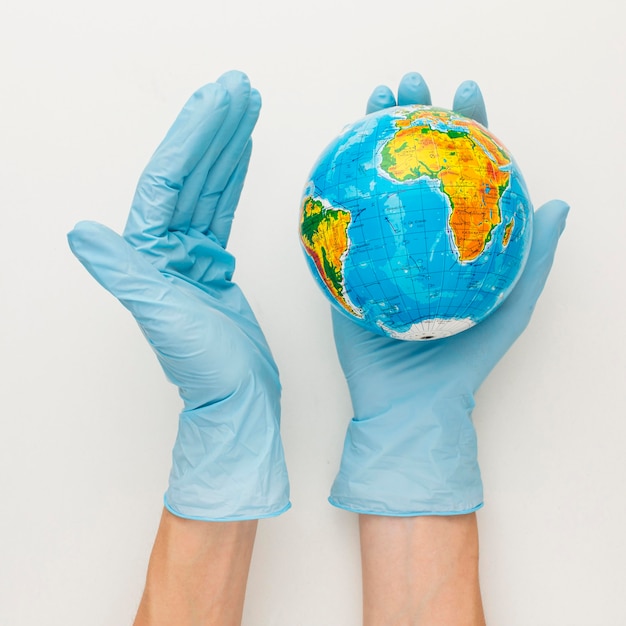 Free Photo top view of hands with gloves holding earth globe