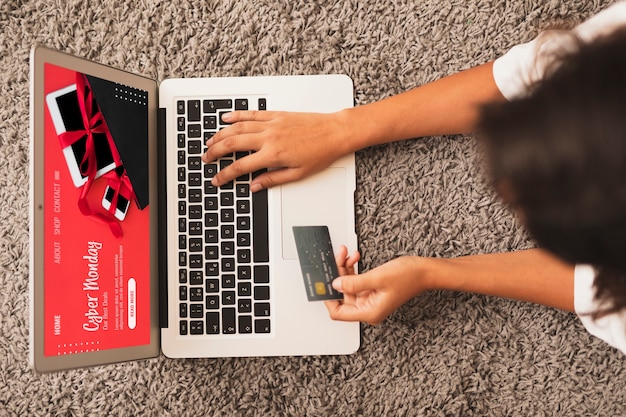 Free photo top view hands writing on laptop and holding a credit card mock up