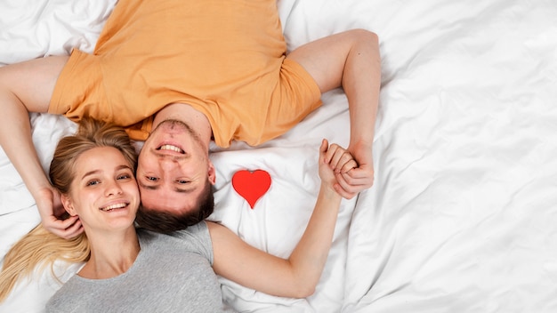 Top view happy couple holding hands in bed