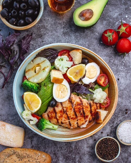 Top view of healthy diet salad with grilled chicken broccoli cauliflower tomato lettuce avocado and lettuce