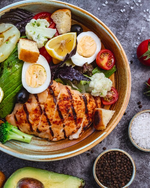 Top view of healthy diet salad with grilled chicken broccoli cauliflower tomato lettuce avocado and lettuce