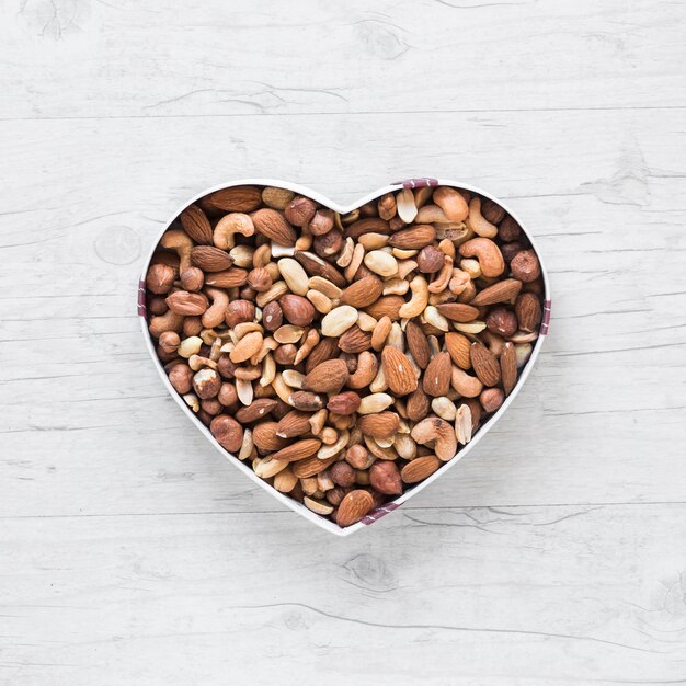 Top view of healthy dryfruits in heart shape on wooden desk