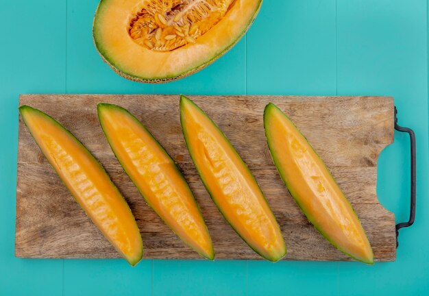 Top view of healthy and fresh melon slices on a wooden kitchen board with on blue surface