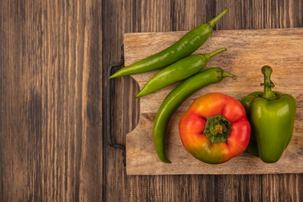 Top view of healthy red and green peppers on a wooden kitchen board on a wooden surface with copy space