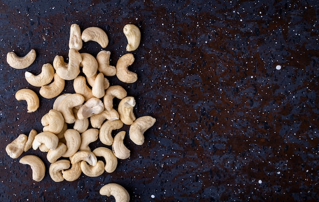 Top view of a heap of cashew nuts on black background with copy s[ace